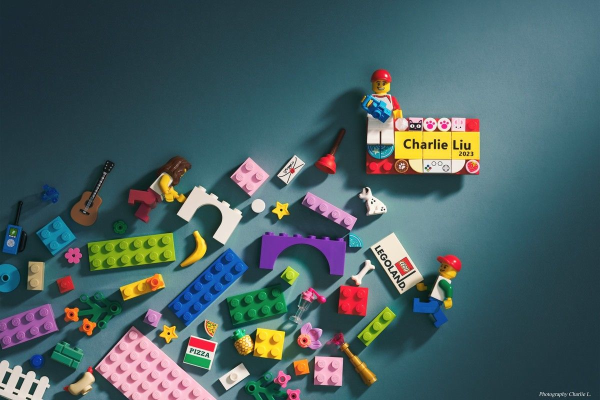 LEGO bricks and a LEGOLAND tile scattered around a brick name plate reading Charlie Liu 2023. Photographed by Charlie Liu.